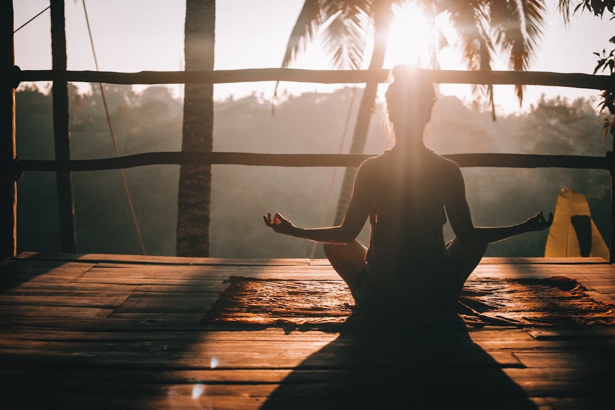 Person meditating in nature at sunrise